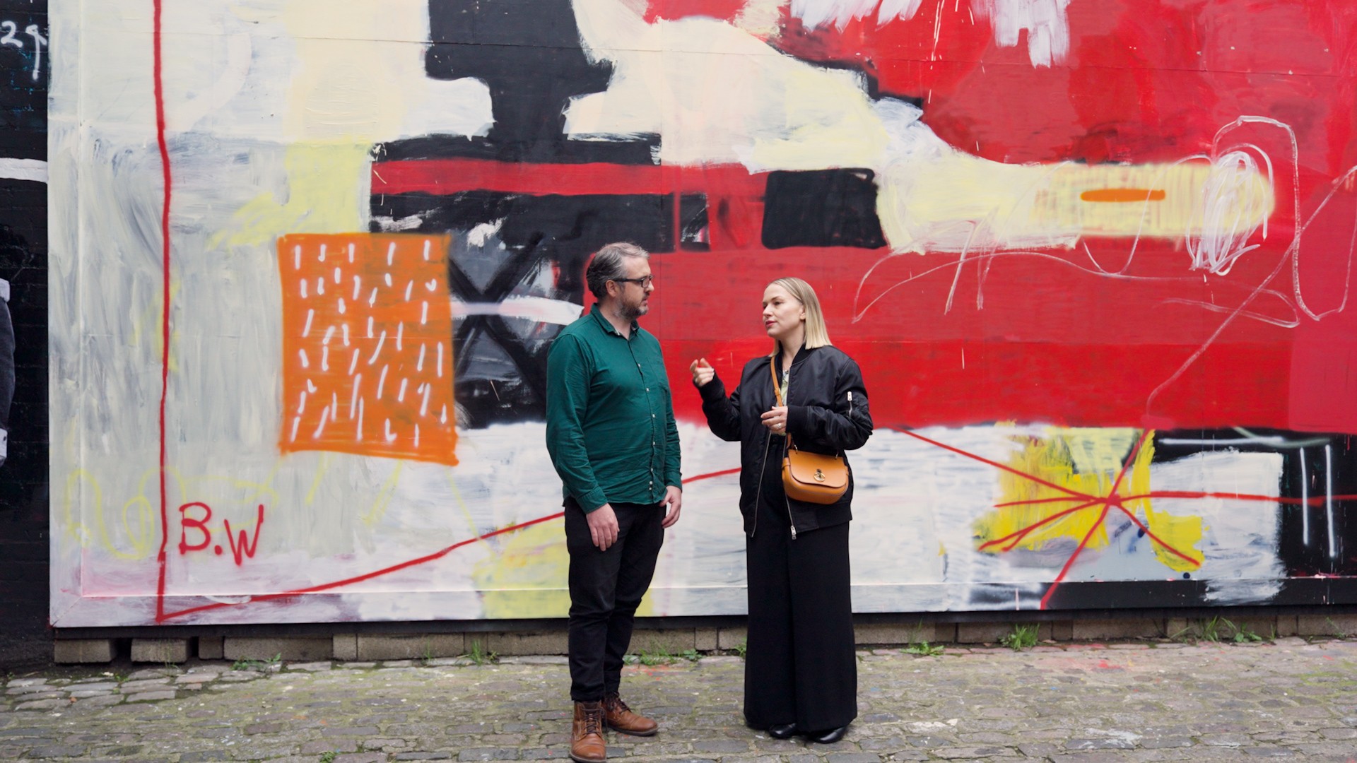 AudioStack Co-Founder and CTO Peadar Coyle and Commercial Director Silke Zetzsche standing in front of a colorful outdoor wall,